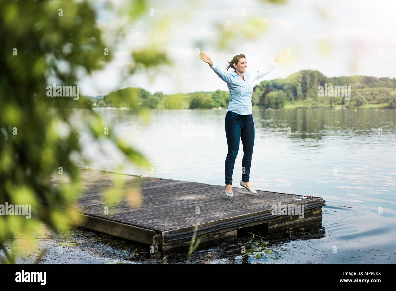 Woman jumping jack sur une jetée à un lac Banque D'Images