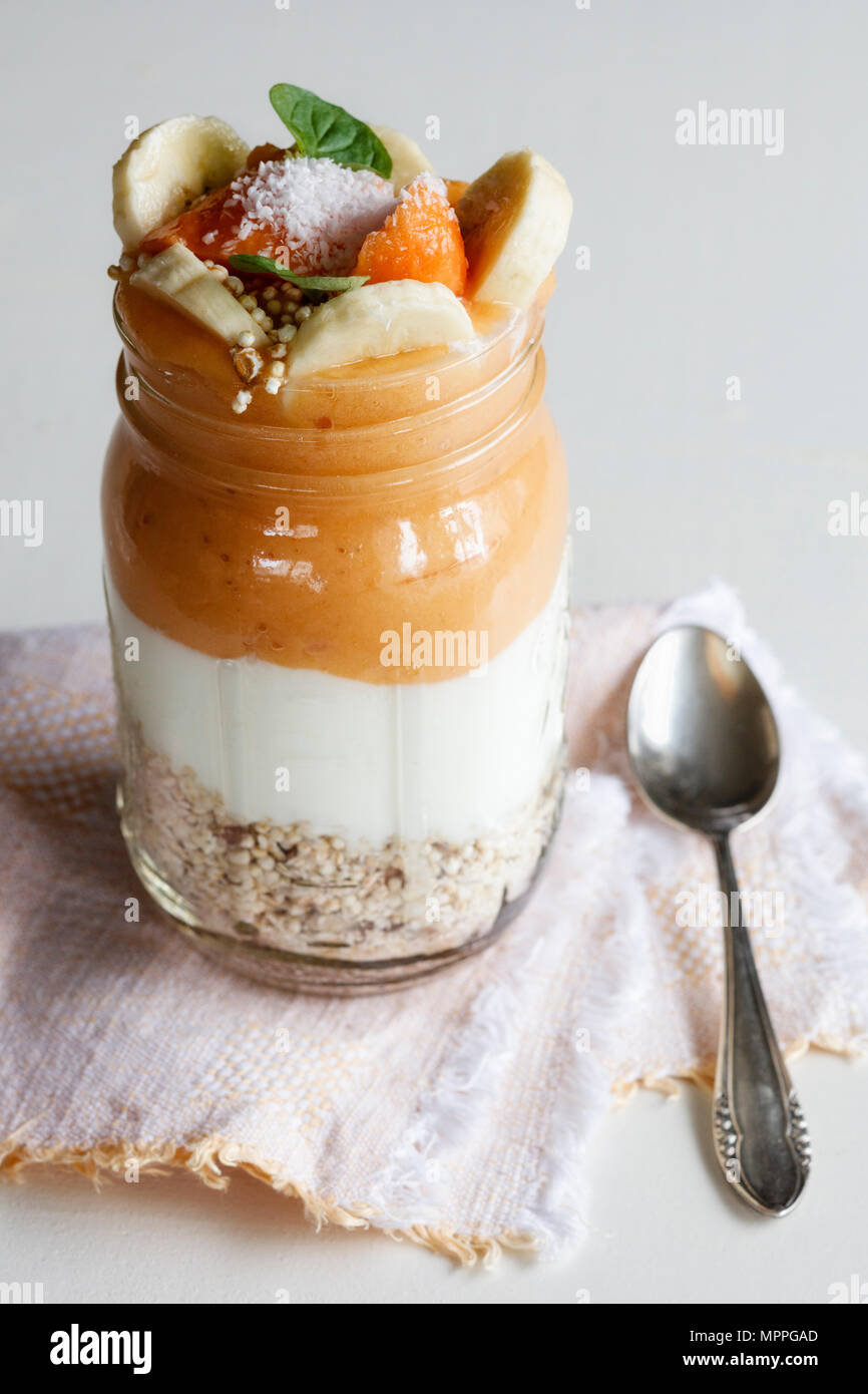 Verre de céréales, de yaourt naturel, papaye Smoothie garni de flocons de noix de coco et fruits Banque D'Images