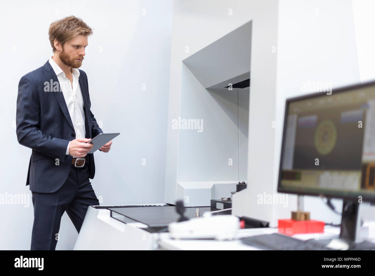 Businessman with tablet à la machine dans l'usine moderne à Banque D'Images