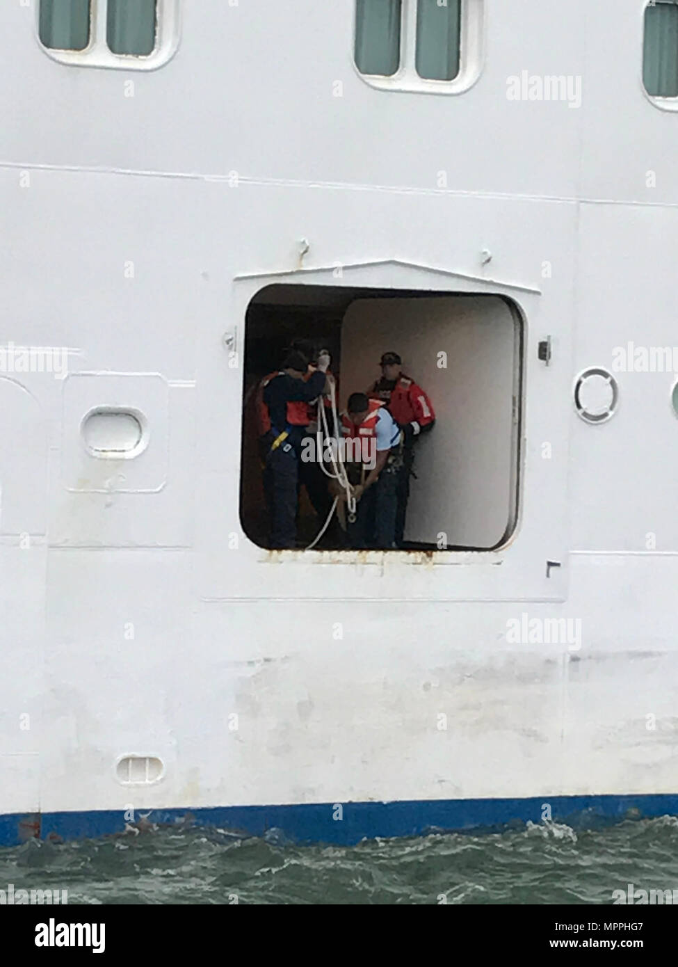 Le personnel de la Garde côtière et de l'équipage avec le bateau de croisière Royal Caribbean International de la grandeur de la mer se préparer pour passer un passager malade à une réponse de 45 pieds de l'équipage Boat-Medium Little Creek Station à l'est de la baie de Chesapeake Bridge Tunnel, 7 avril 2017. La Garde côtière a reçu un appel du personnel des navires de croisière qu'un homme de 60 ans était passager souffrant d'arrêt respiratoire d'urgence nécessaires et transport à terre. (U.S. Photo de la Garde côtière du Maître de 2e classe Geoffrey Wells/libéré) Banque D'Images
