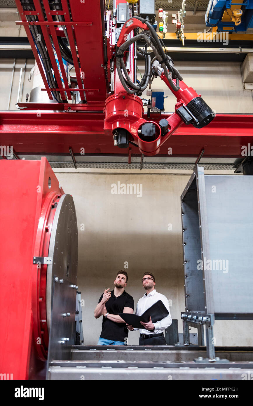 Avec deux hommes à la recherche de dossier à l'atelier en usine sur la machine Banque D'Images