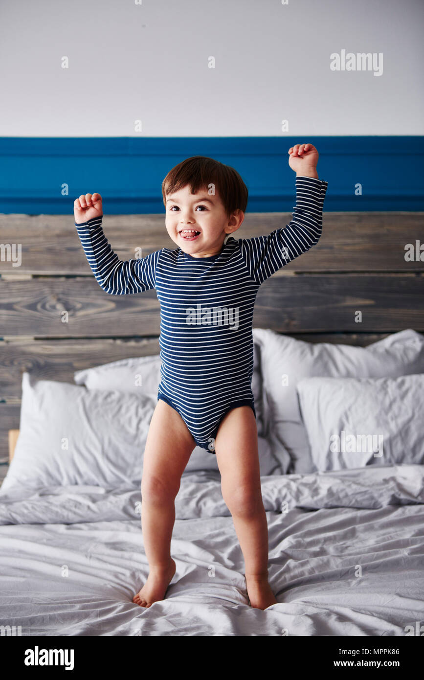 Portrait of happy toddler jumping on bed Banque D'Images