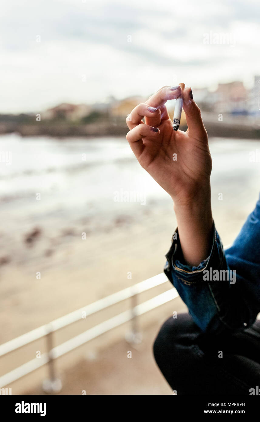 Main d'une femme qui fume une cigarette dans un village côtier Banque D'Images