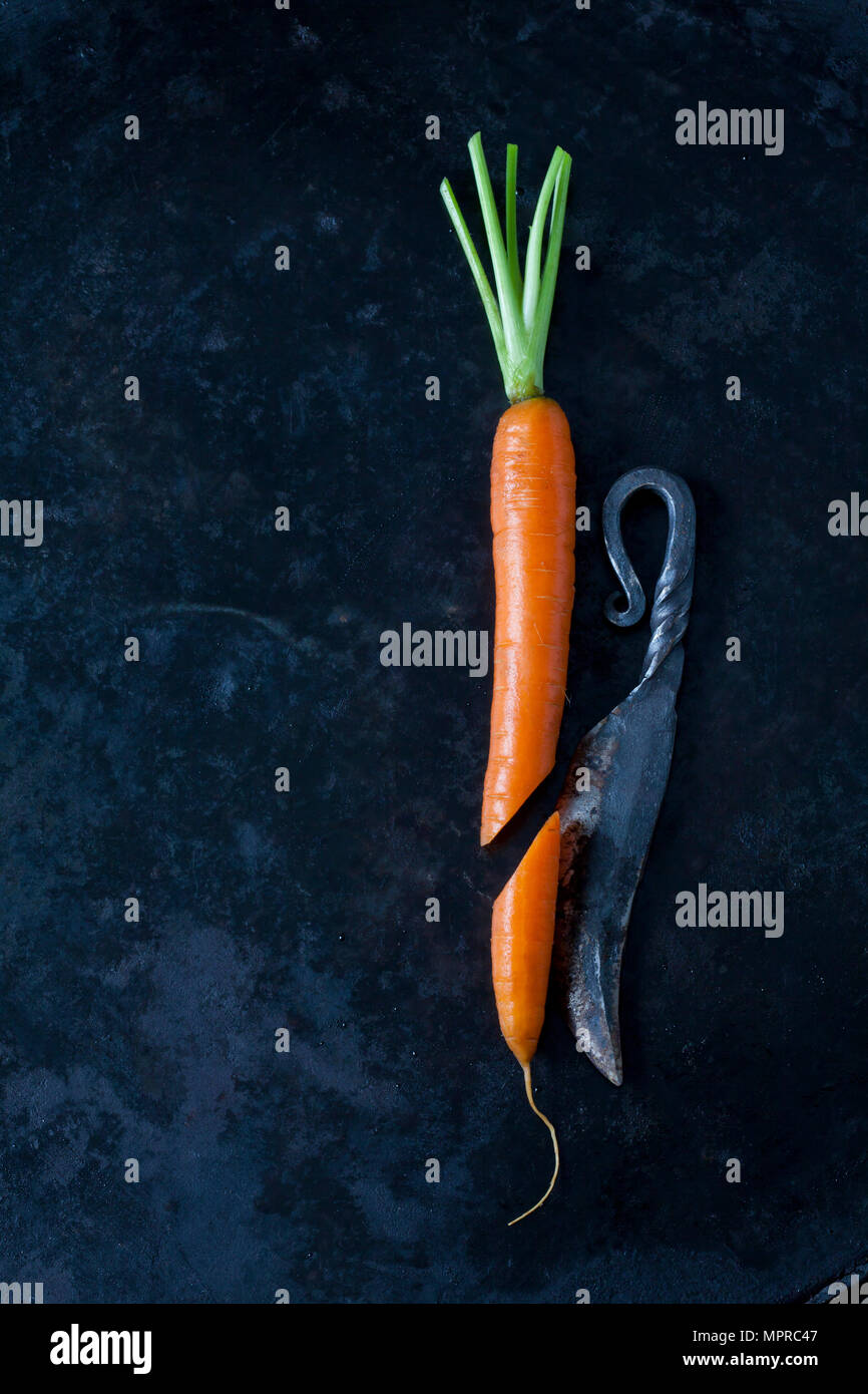 Une carotte en tranches un vieux couteau sur la masse sombre Banque D'Images