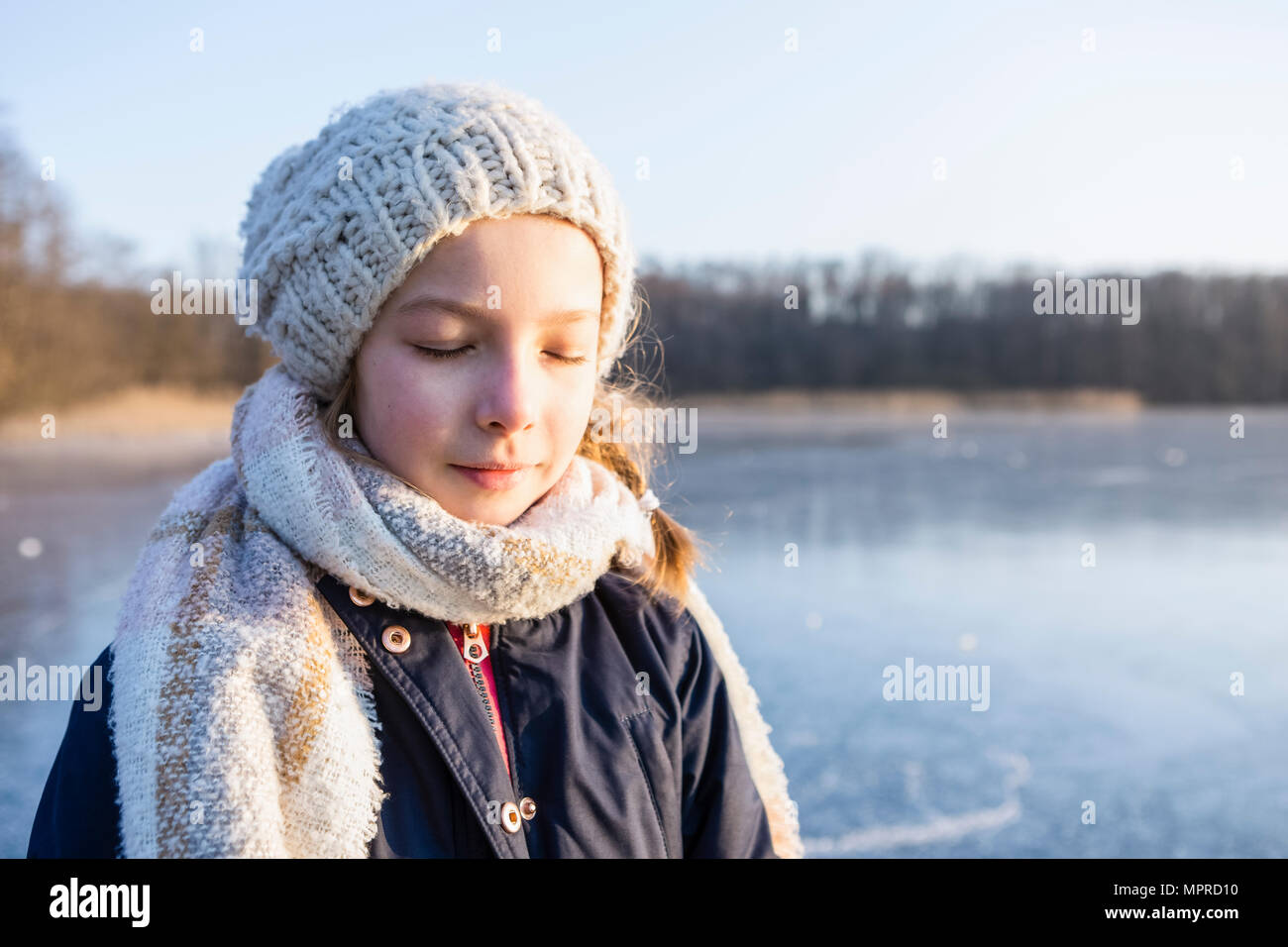 Allemagne, Brandebourg, lac Straussee, portrait d'une jeune fille debout sur le lac gelé, les yeux fermés Banque D'Images