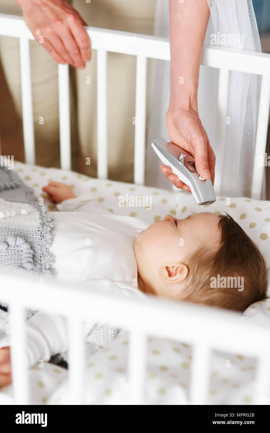 Thermomètre numérique avec mère la température de bébé en crèche Banque D'Images