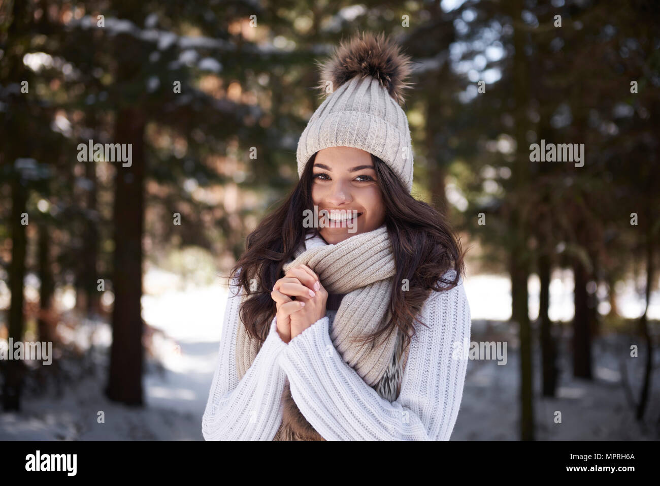 Portrait of happy young woman wearing knitwear en forêt d'hiver Banque D'Images