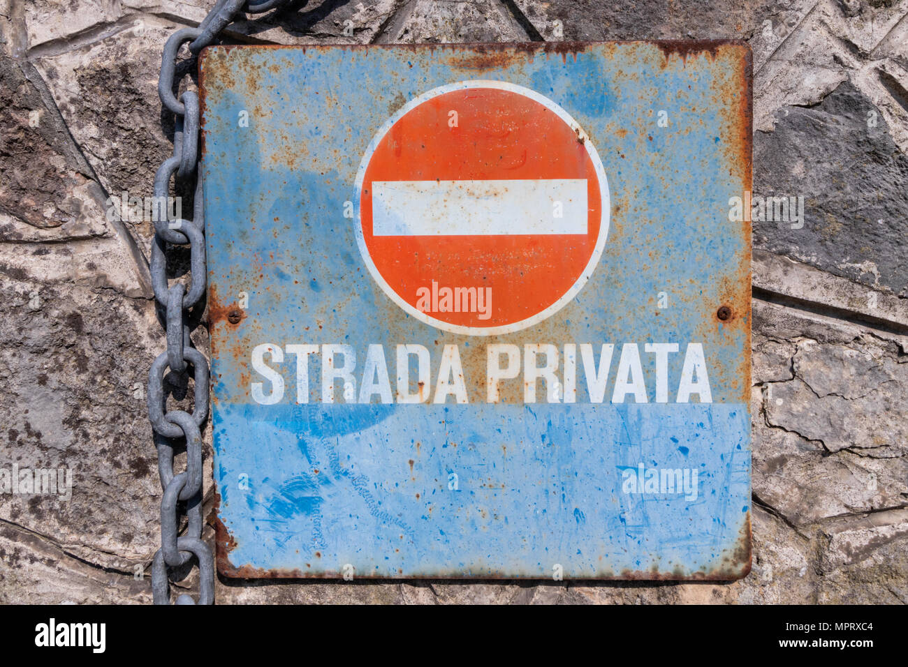 Pas d'entrée panneau italien rouillé avec indication d'un chemin privé fixé sur un mur de pierre et d'une chaîne Banque D'Images