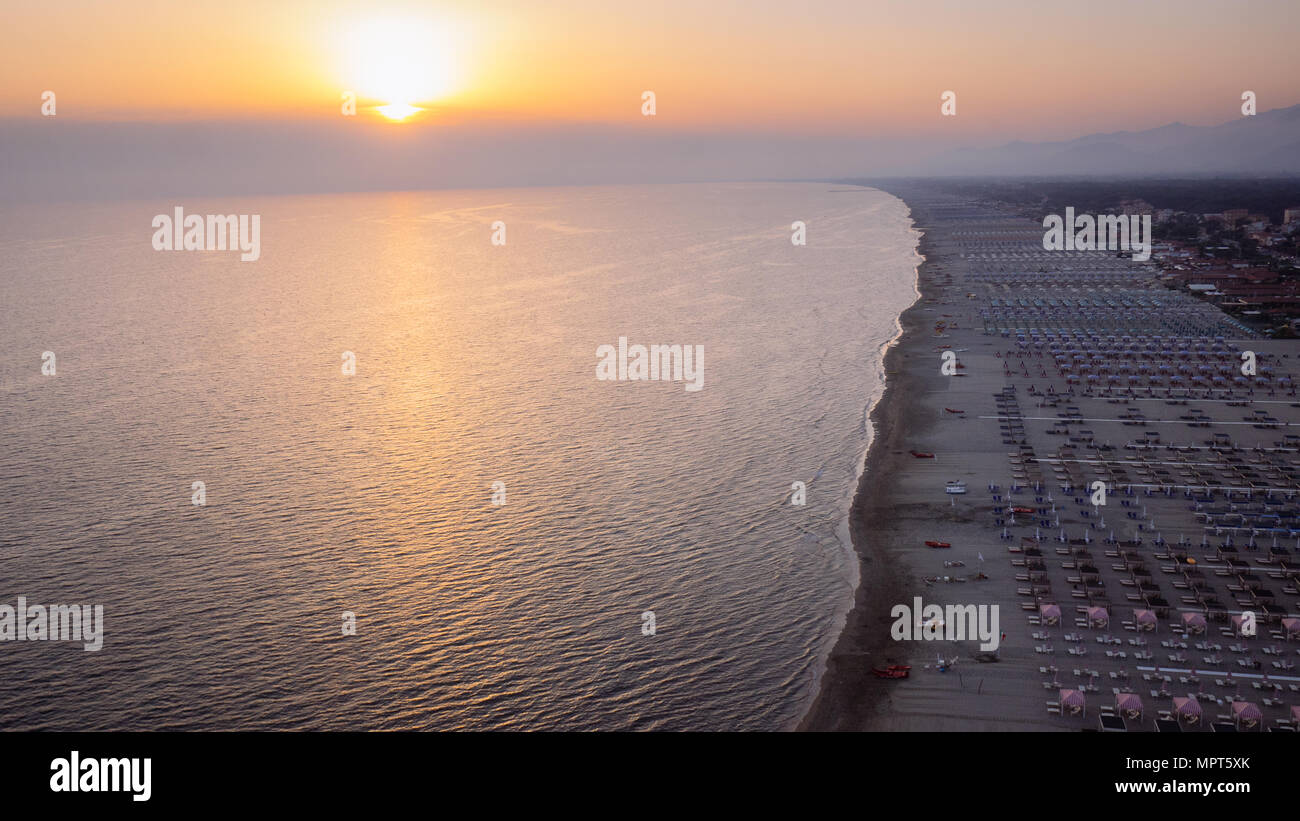 Foggy coucher de soleil sur la côte de la Versilia, 20 km de côte en toscane arraisonné par les Alpes Apuanes et souligné par des parasols et sièges Banque D'Images