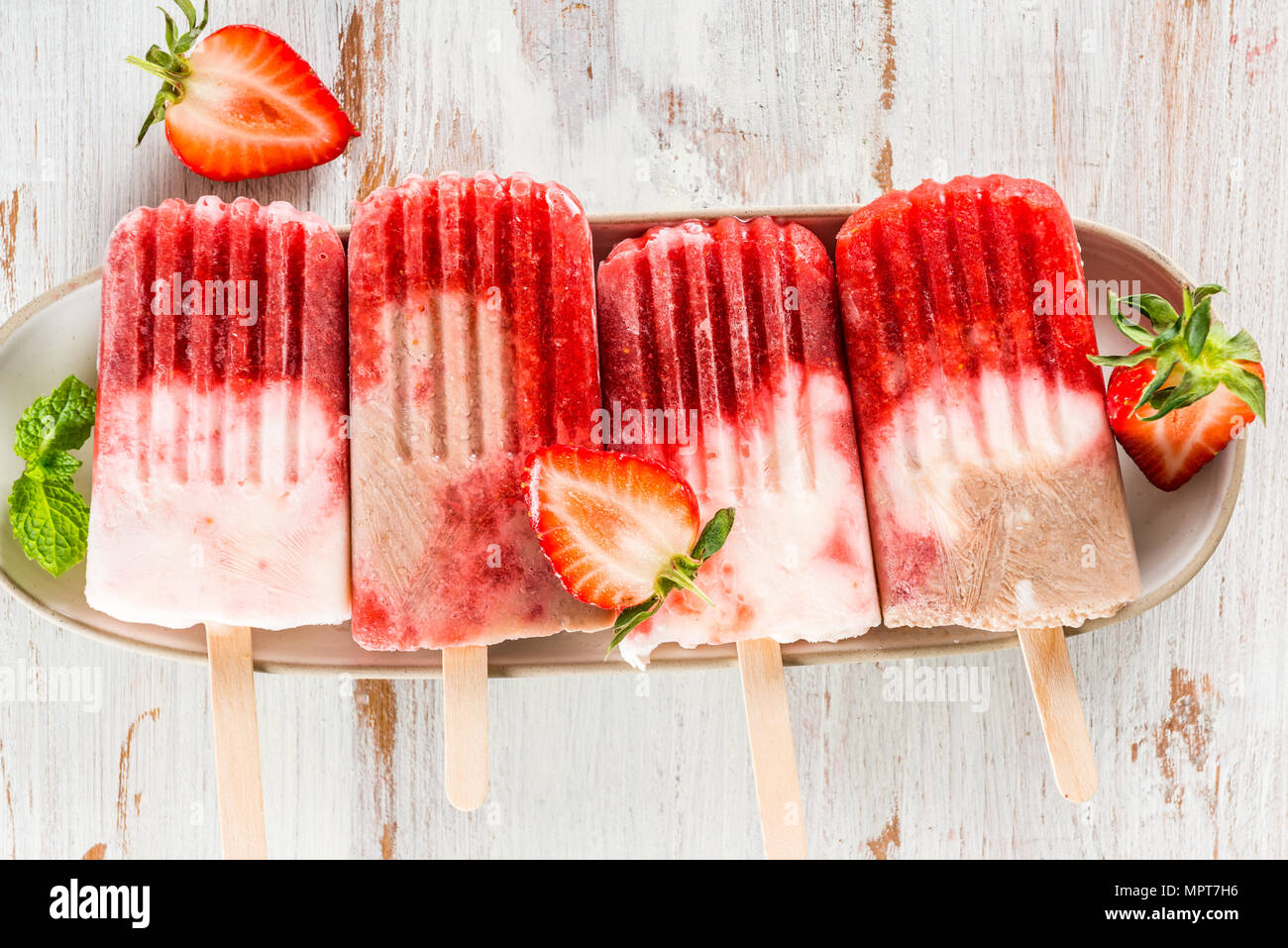 Vegan fait maison de Popsicle Fraise Jus de fraises et le lait de coco sur fond de bois clair. Concept des aliments en été. Vue d'en haut. Banque D'Images