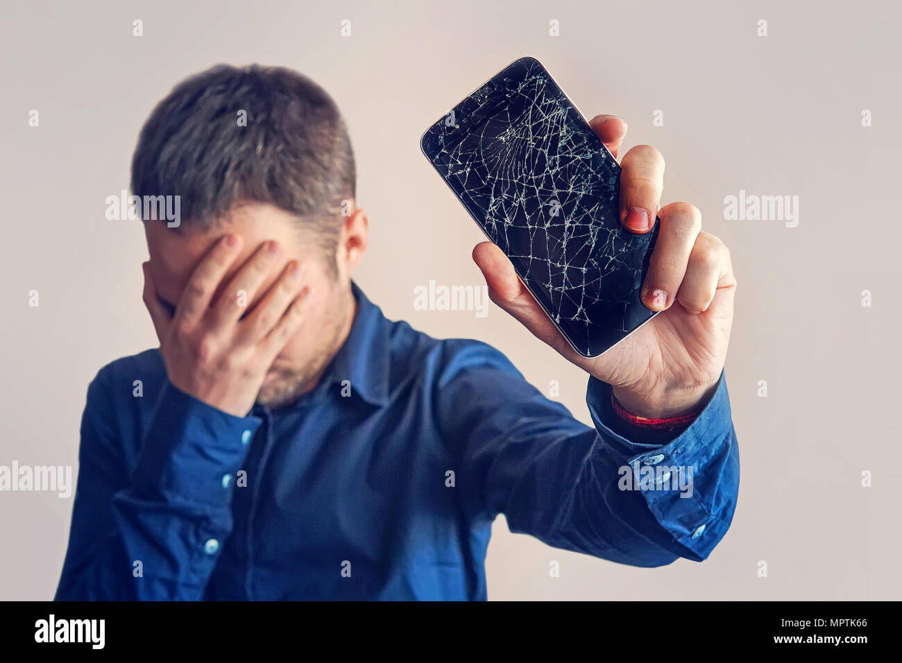 Le mec est maintenant un smartphone noir avec un écran cassé. Écran cassé sans cadre moderne de téléphone. guy pleurer avec ses yeux fermés et les mains dans son Banque D'Images