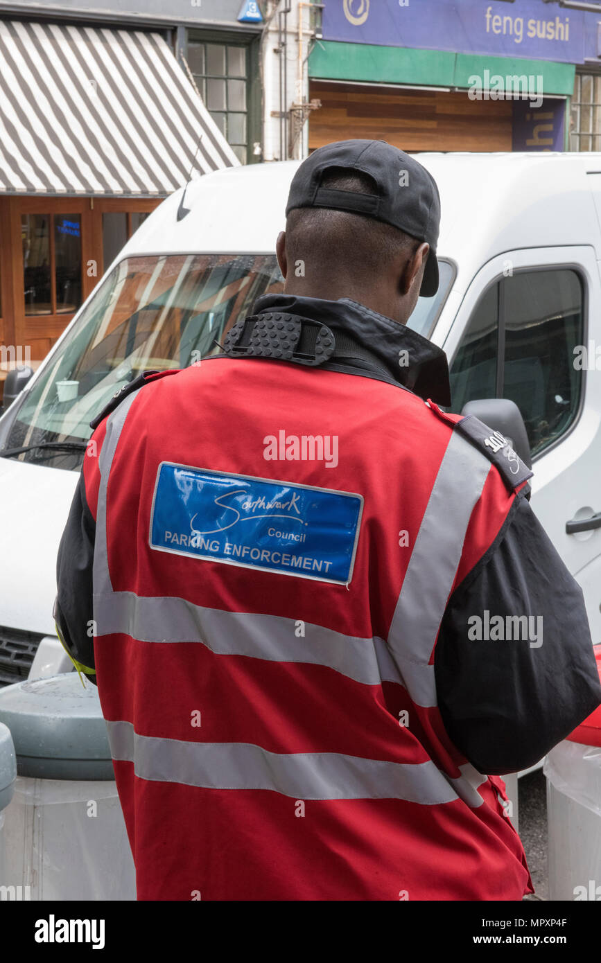 Un gardien de parking ou agent de l'émission d'un billet pour une infraction de stationnement à Borough Market à Londres. Conduite automobile et stationnement des amendes. Banque D'Images