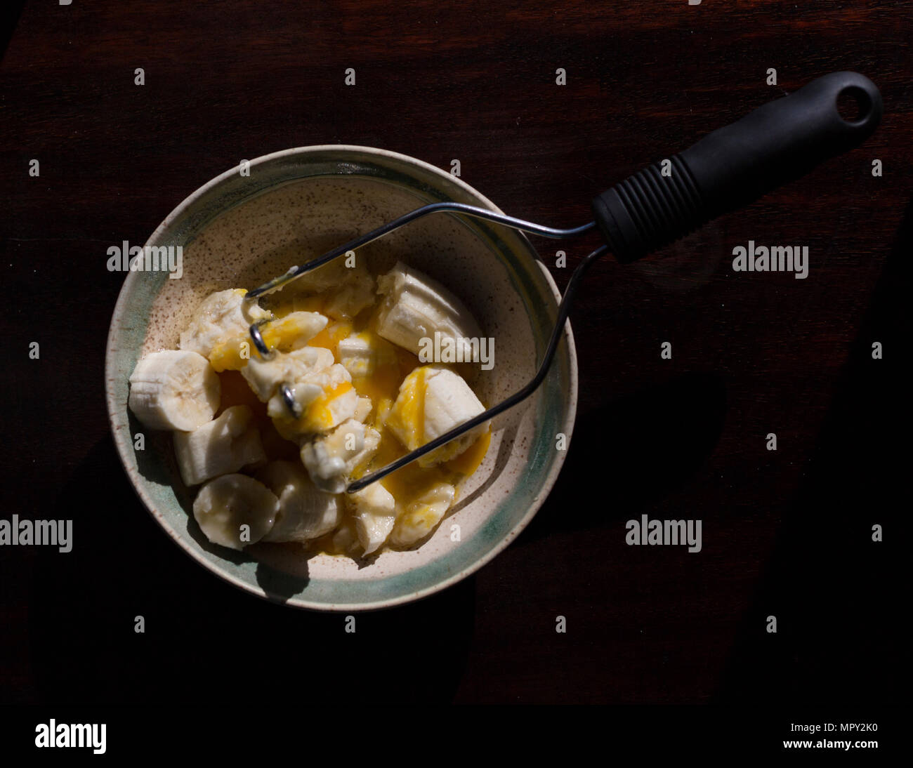 Vue de dessus de tranches de banane et les oeufs dans un bol avec piler sur table Banque D'Images