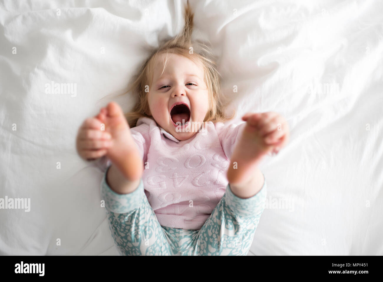 Portrait of happy baby girl lying on bed at home Banque D'Images