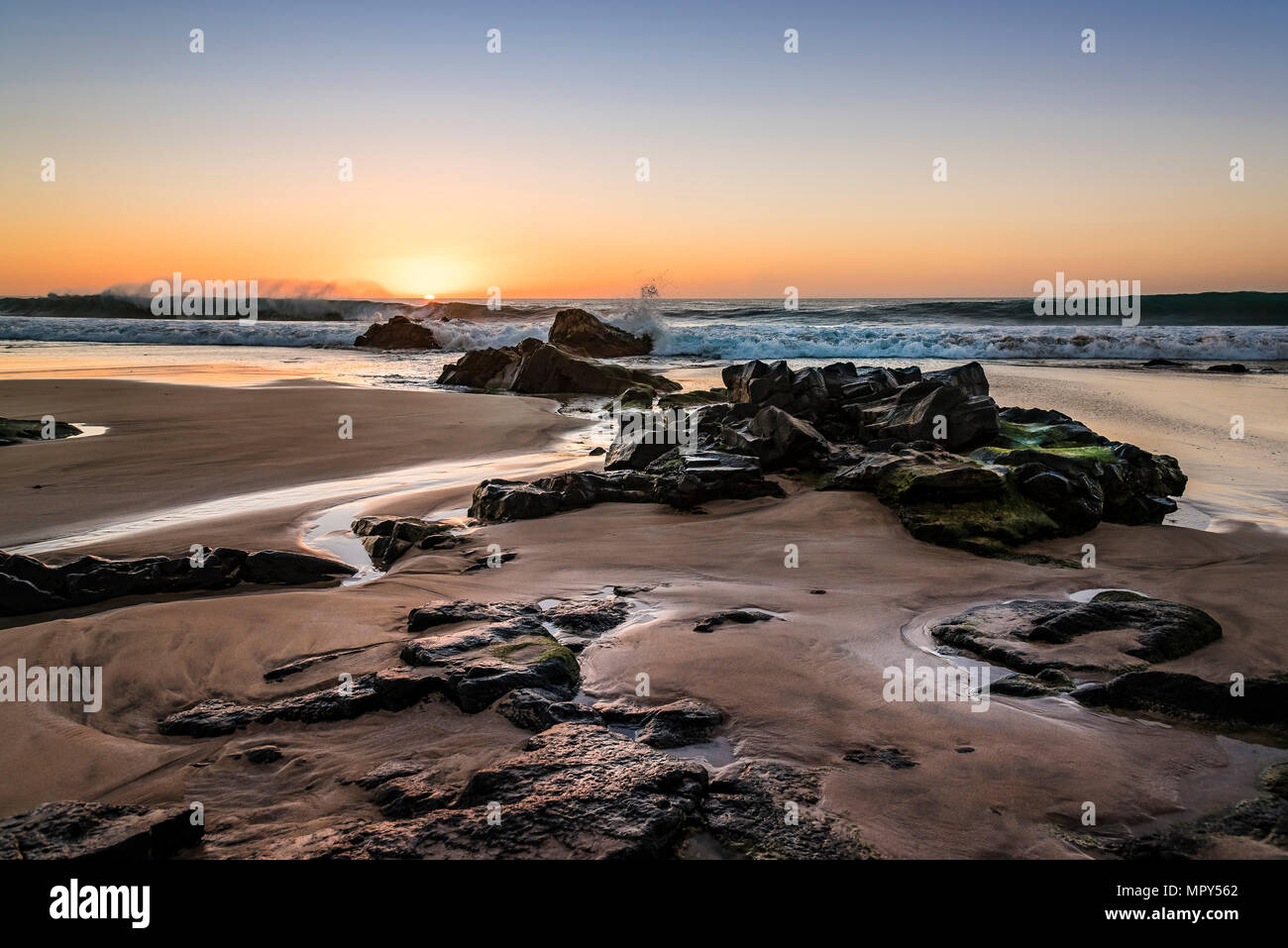 Vue idyllique sur la mer avec plage de rochers à contre ciel dramatique pendant le coucher du soleil Banque D'Images