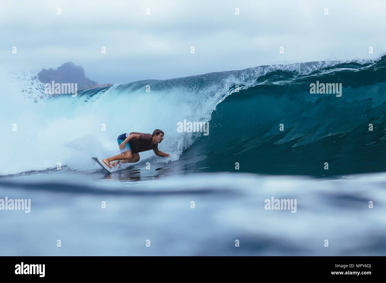 Homme surf sur mer contre ciel nuageux Banque D'Images