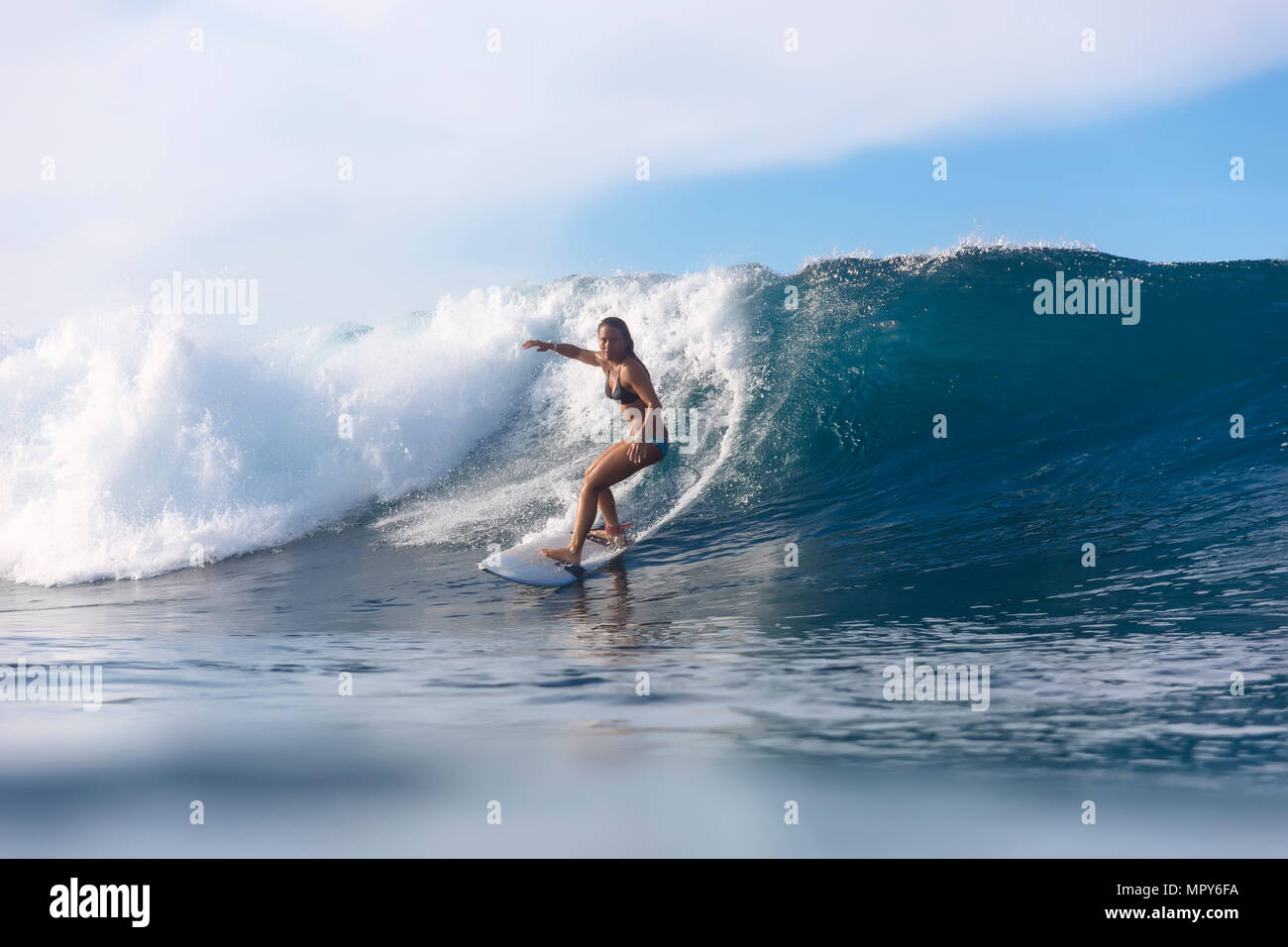 Femme surf sur mer contre ciel nuageux Banque D'Images