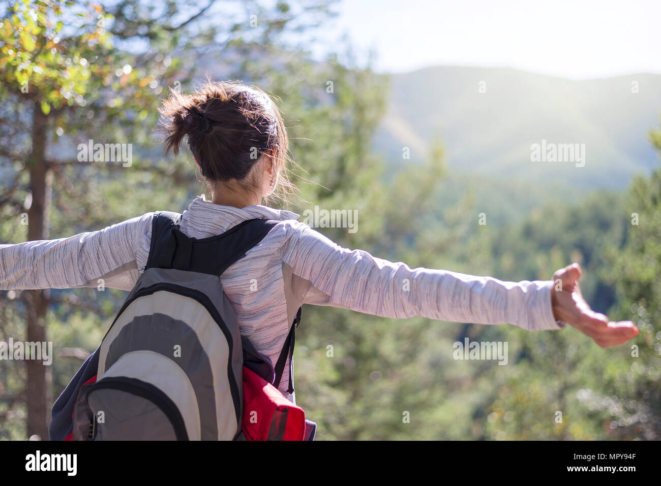 Backpacker sans souci avec les bras tendus à la vue de tout en se tenant dans forêt durant journée ensoleillée Banque D'Images