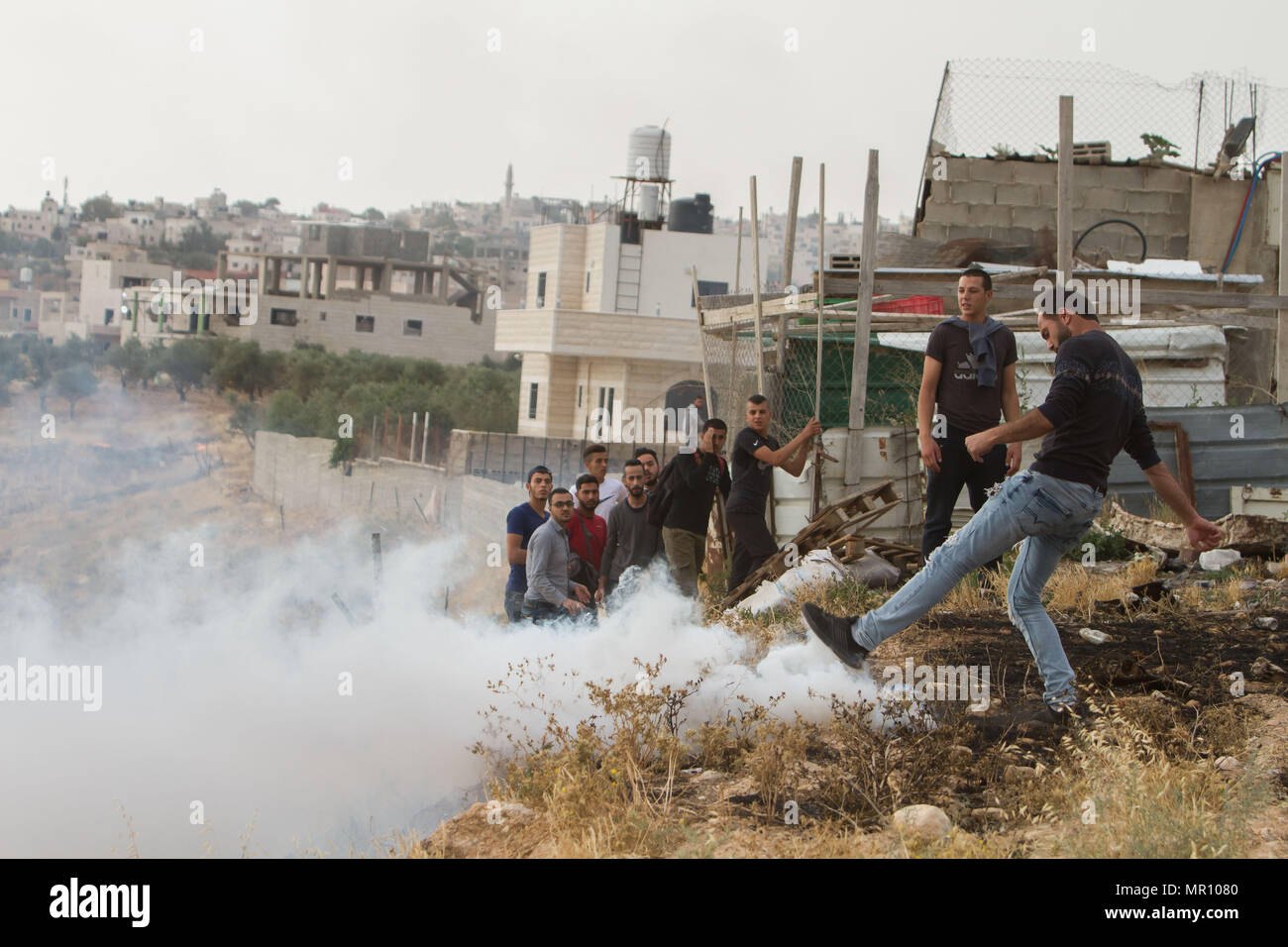 Bethléem, ville de Cisjordanie Bethléem. 25 mai, 2018. L'un des Palestiniens, qui a tenté de grimper la barrière controversée de traverser Jérusalem de la Cisjordanie et ont été interdit par les forces de sécurité israéliennes, coups une grenade de gaz lacrymogène tiré par les forces de sécurité israéliennes, alors qu'ils prennent leur façon de participer à la deuxième Ramadan prière du vendredi à Jérusalem, mosquée al-Aqsa, près de la ville cisjordanienne de Bethléem, le 25 mai 2018. Credit : Luay Sababa/Xinhua/Alamy Live News Banque D'Images