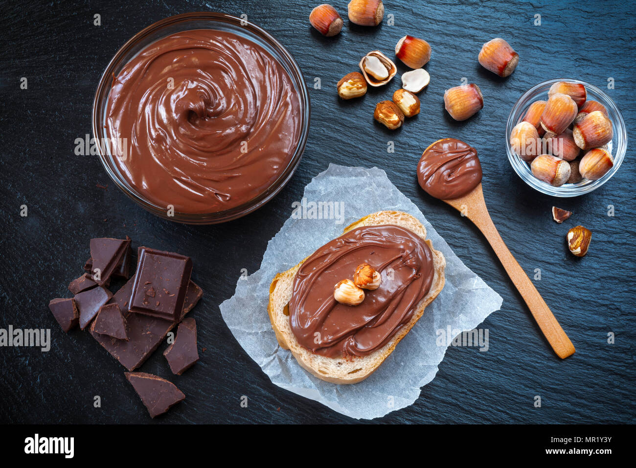 Tranche de pain avec la crème au chocolat et noisettes propagation sur le tableau noir. Servant un délicieux petit-déjeuner gratuit. Banque D'Images
