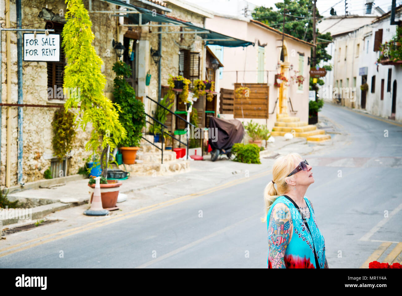 Femme d'âge moyen, vêtue de façon décontractée, regardant vers le haut, explorant le petit village de montagne de Bellapais, le nord du Cypress. Banque D'Images