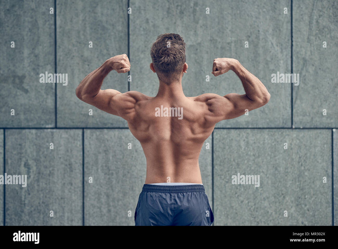 Young male bodybuilder posing with dos à la caméra Banque D'Images