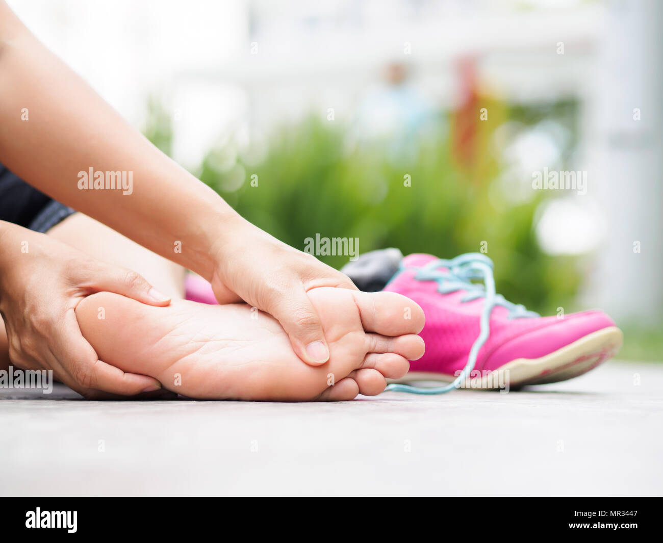 Femme libre en massant son pied douloureux tout en s'exerçant. L'exécution de blessures de sport concept. Banque D'Images