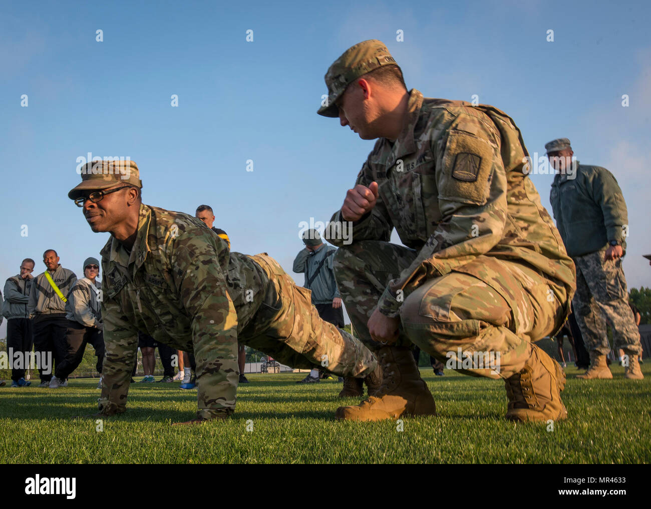 Réserve de l'armée américaine le Sgt. 1re classe Timothy Onderko (à genoux), de Lawton, Oklahoma, montres un soldat démontrer le bon formulaire pour push-ups pour les membres de la 335e la commande Signal (Théâtre) avant qu'un test de condition physique de l'armée à East Point, Géorgie, le 6 mai 2017. L'APFT est conçu pour tester la force musculaire, l'endurance, et de remise en forme respiratoire cardiovasculaire des soldats dans l'armée. Les soldats sont évalués sur la base de leurs performances dans trois activités contenant des push-up, Sit-up et un deux-mile run, allant de 0 à 100 points dans chaque cas. (U.S. Réserve de l'armée photo prise par le s.. Ken Scar) Banque D'Images