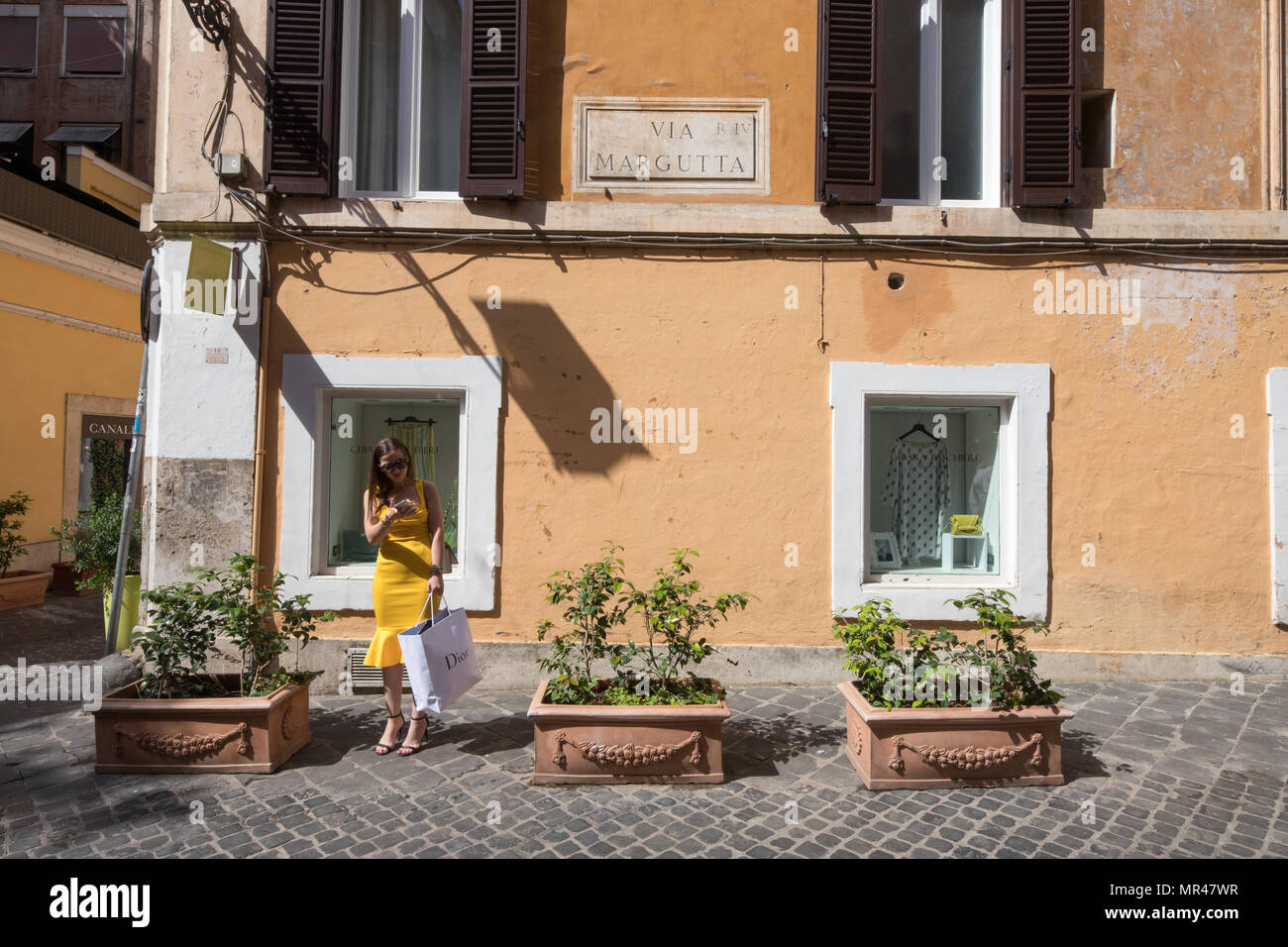 Rome Via Margutta, la rue des artistes famouse, actractive femme avec robe de chambre jaune et panier en attente dans la rue. Scène Rome Italie Banque D'Images