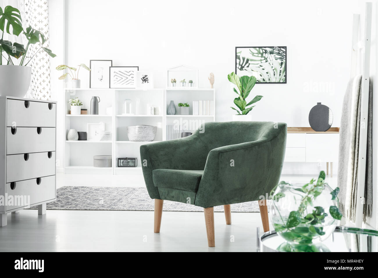 Fauteuil vert en blanc intérieur chambre avec un placard, décorations sur des étagères et des plantes Banque D'Images