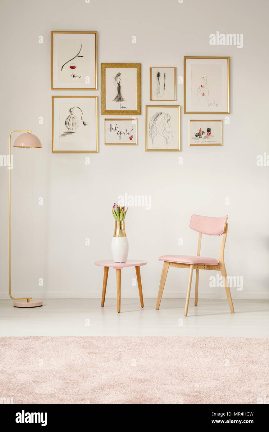 Peintures dans des cadres d'or rose, chaise, table et lampe fixée sur le mur blanc dans un coin salon intérieur Banque D'Images