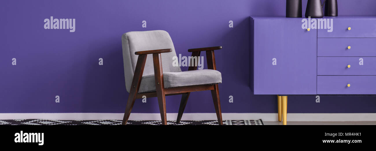 Fauteuil gris debout à côté d'un placard dans la chambre pourpre violet intérieur avec place pour votre table Banque D'Images