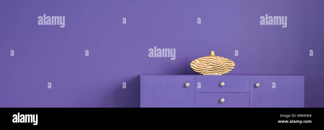 Vase décoratif d'or placée sur un placard en bois debout en violet violet prix intérieur avec l'espace vide de votre placement de produit Banque D'Images