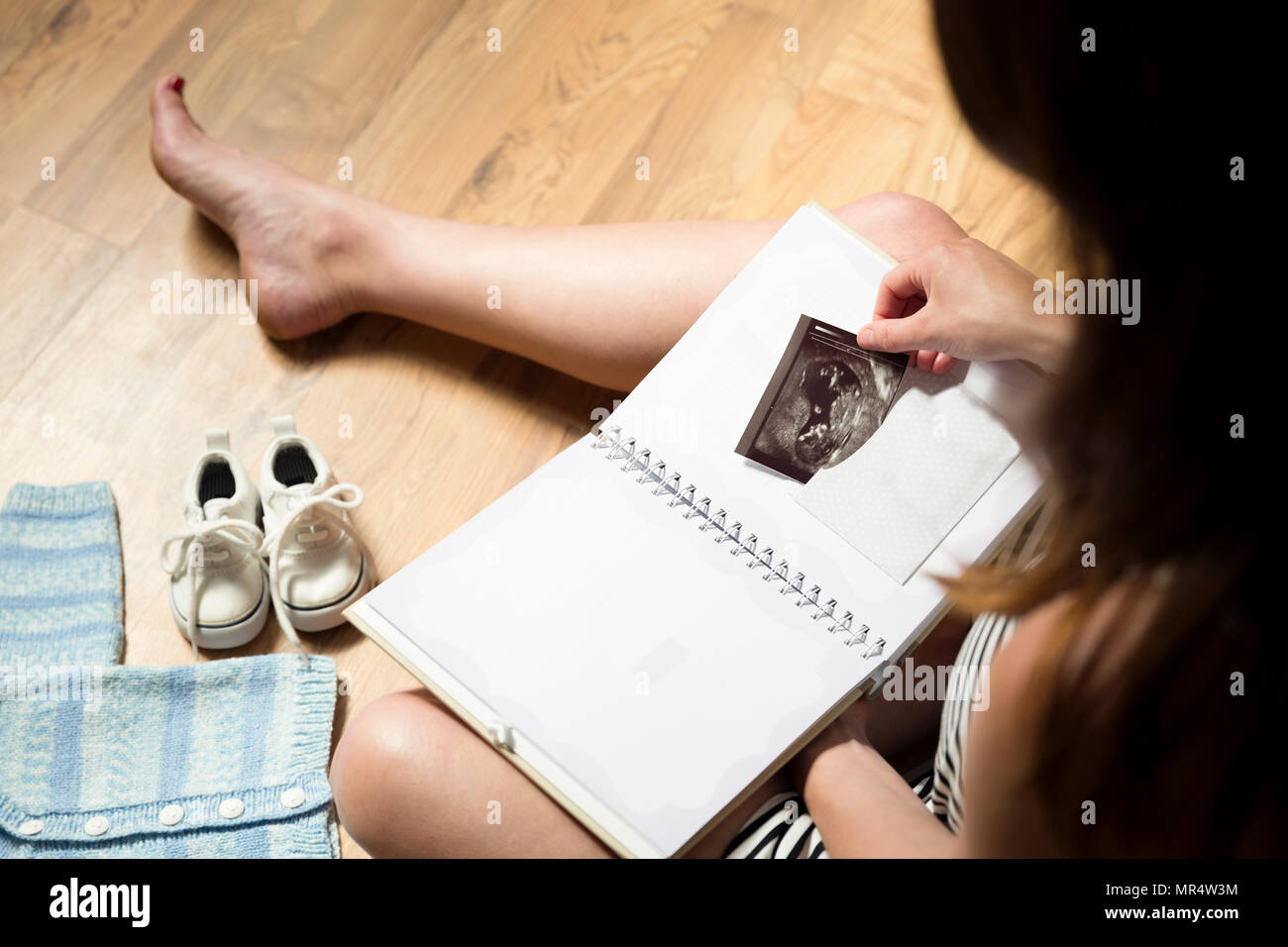 Femme De Placer Bebe Sonogramme Dans La Premiere Annee Du Bebe Livre De Memoire Vetements De Bebe Et Des Chaussures Portant Sur Le Plancher Photo Stock Alamy