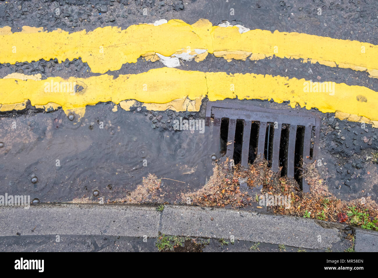 L'eau de pluie coulant le long d'une gouttière de la rue dans un drain, Lancashire, England, UK Banque D'Images