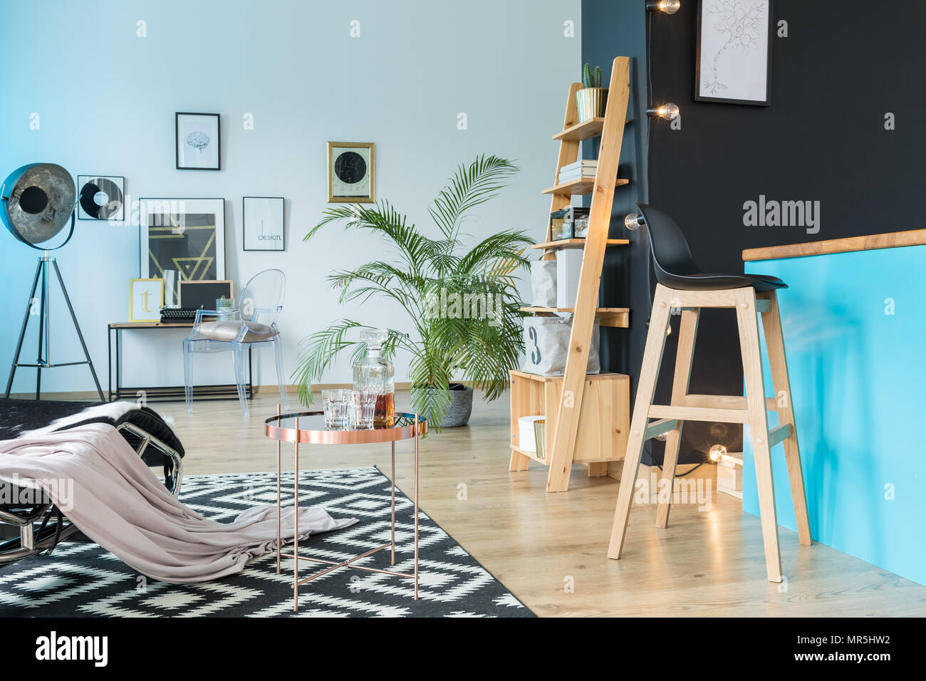 Salle de détente spacieuse avec tabouret de cuisine à l'île et étagère en bois sur mur noir Banque D'Images