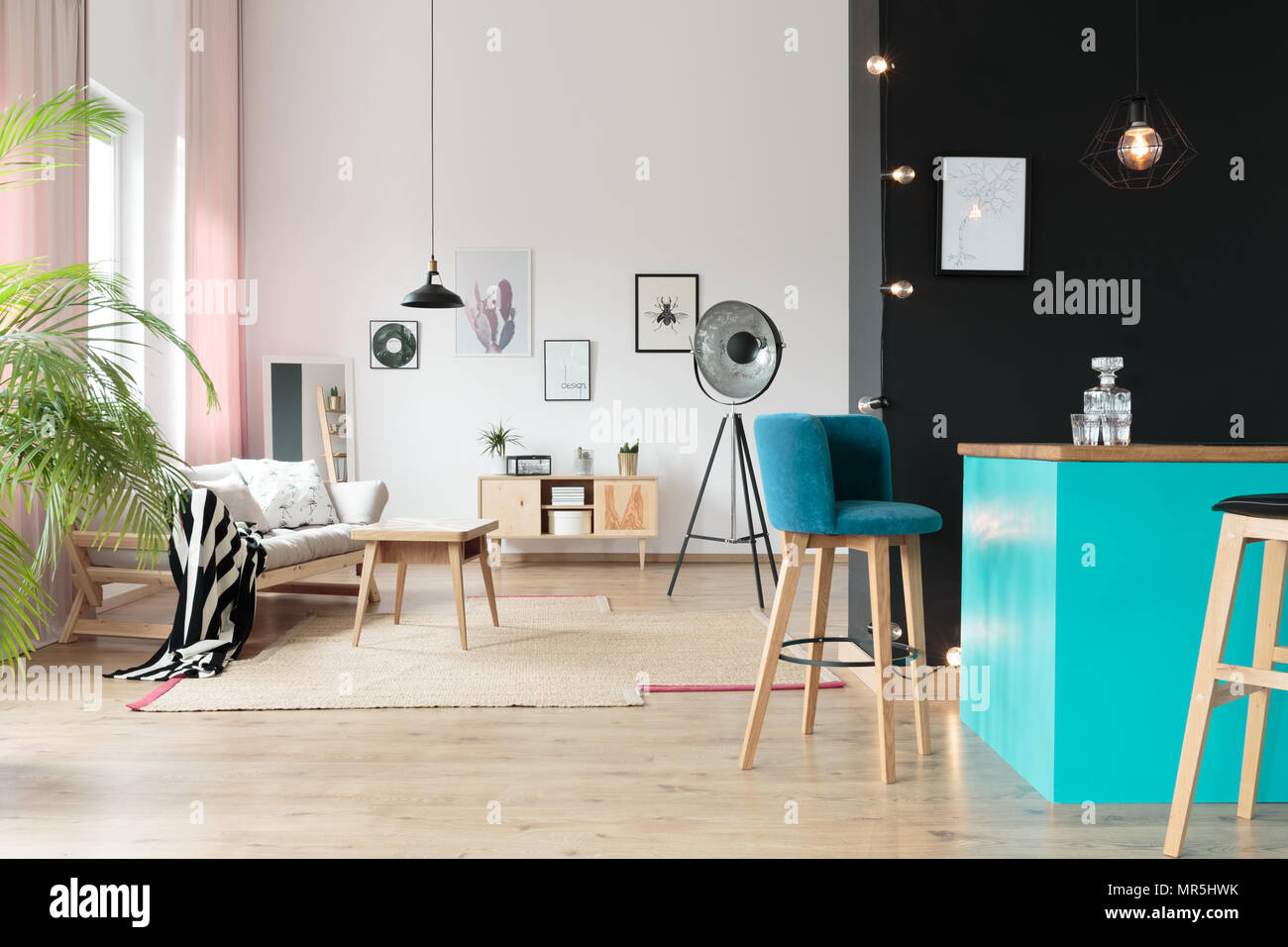 Lampe design ouvert dans l'espace détente avec tabouret en daim bleu au minibar contre mur noir Banque D'Images