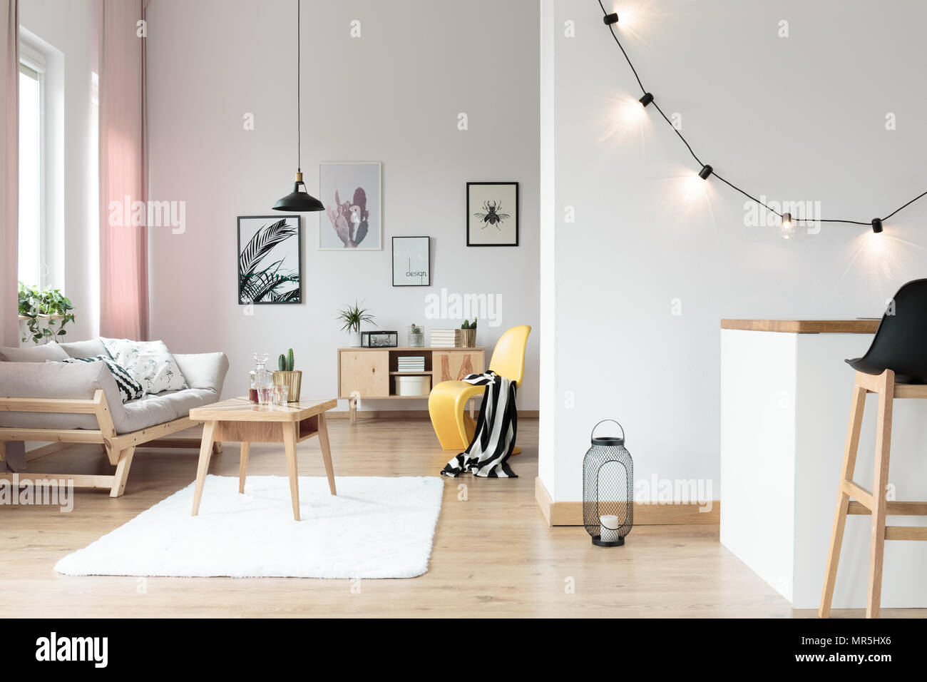 Dans l'éclairage salon lumineux avec couverture à rayures jaune sur chaise à côté de table sur tapis blanc Banque D'Images