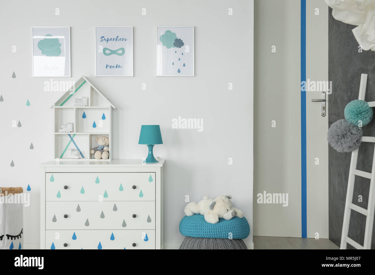 Chambre bébé blanc avec buffet, pouf et affiches de murs Banque D'Images