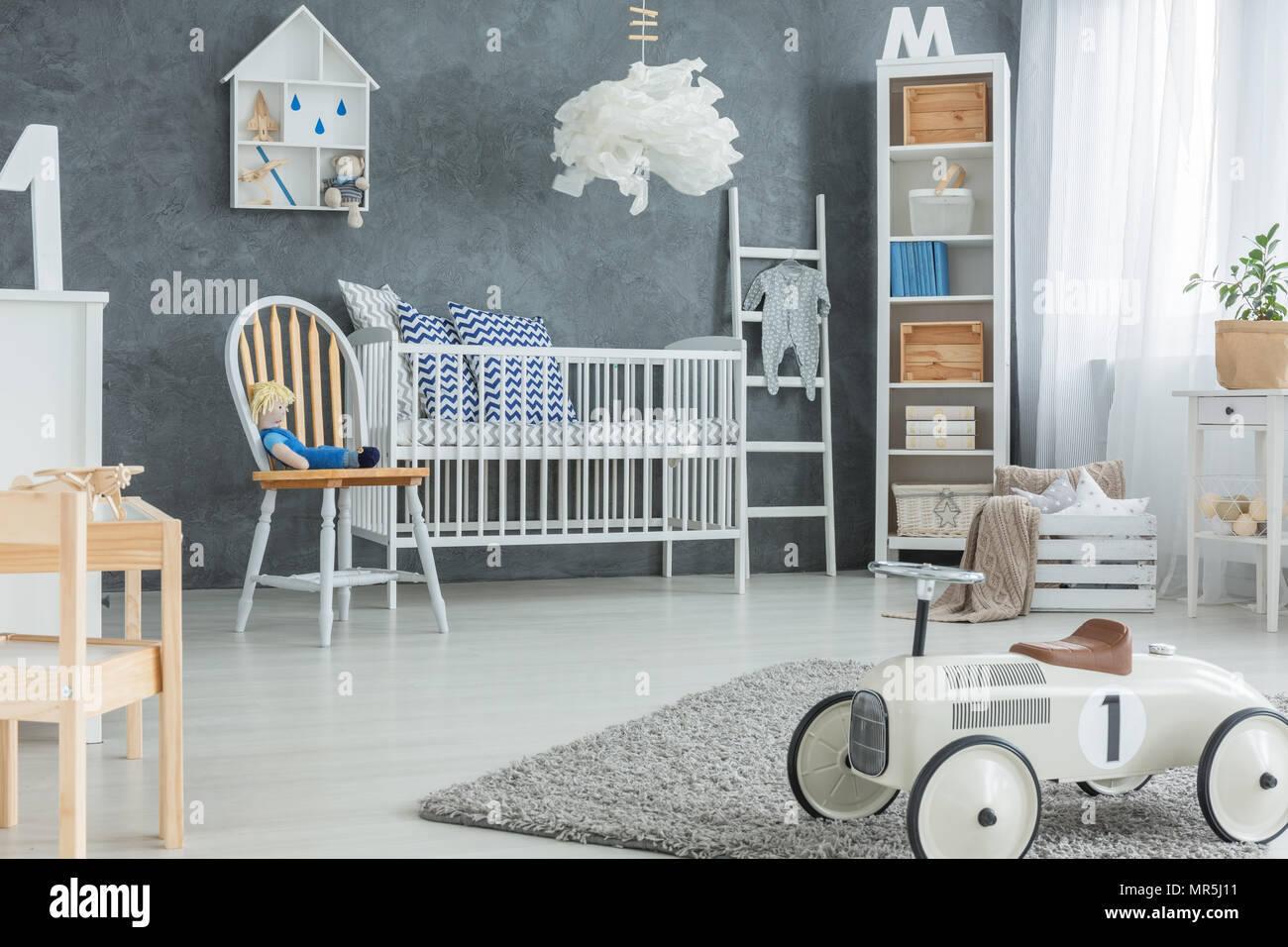 Chambre garçon gris blanc avec lit bébé, Bibliothèque et rug Banque D'Images