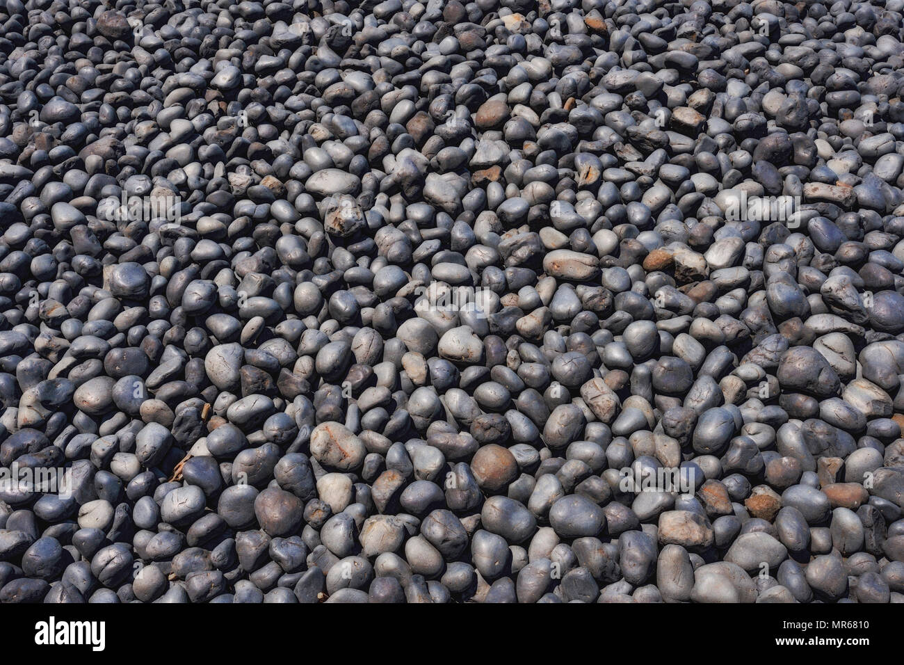 Clsoeup de cobble stones sur galets à Newport, Oregon. Les pierres sombres formées à partir de la lave érodée au cours de millions d'années par la mer. Banque D'Images