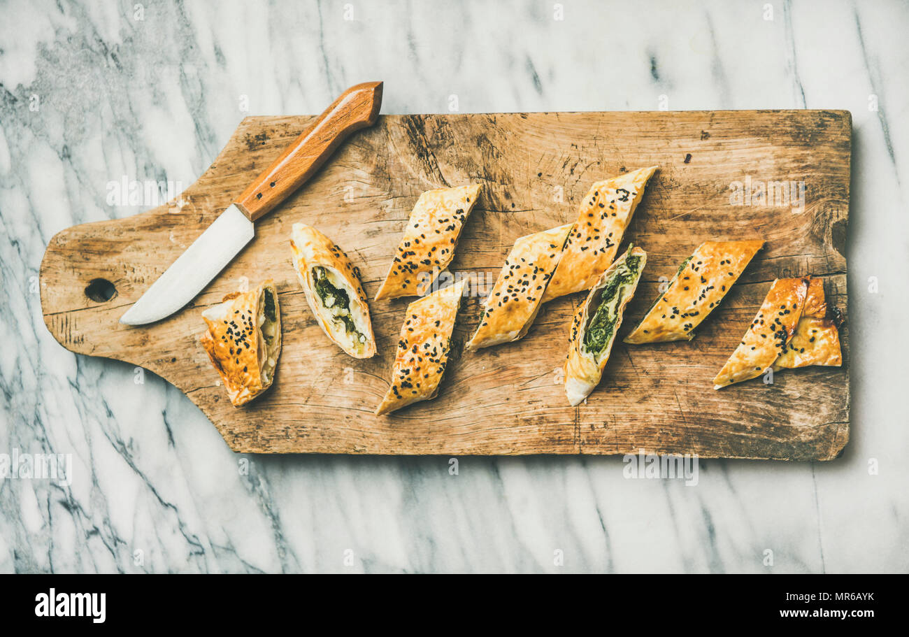 Télévision à jeter de Borek turc avec les épinards, les tranches de rouleau de feta et les graines de cumin sur planche de bois sur fond de marbre gris, top v Banque D'Images