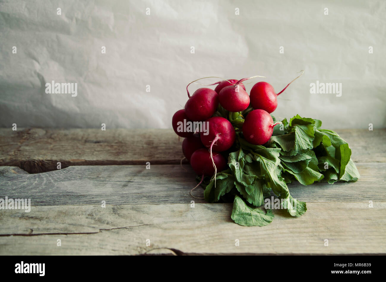 Tas de radis frais avec des dessus et des feuilles sur fond rustique en bois avec copie espace Banque D'Images