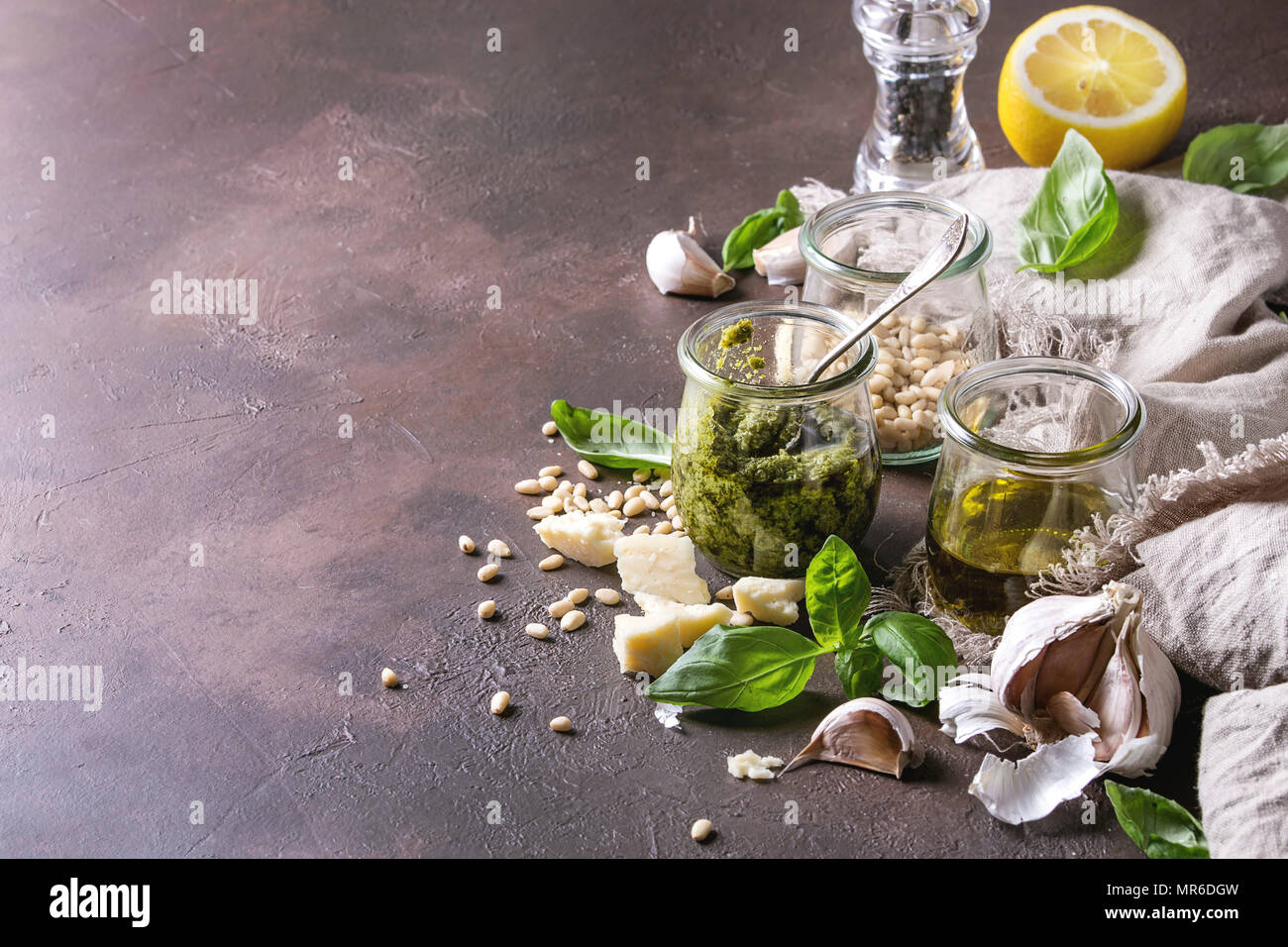 Sauce Pesto au basilic traditionnel dans un bocal en verre avec les ingrédients ci-dessus le basilic frais, l'huile d'olive, le parmesan, l'ail, les pignons de pin, citron sur tissu sur dark Banque D'Images