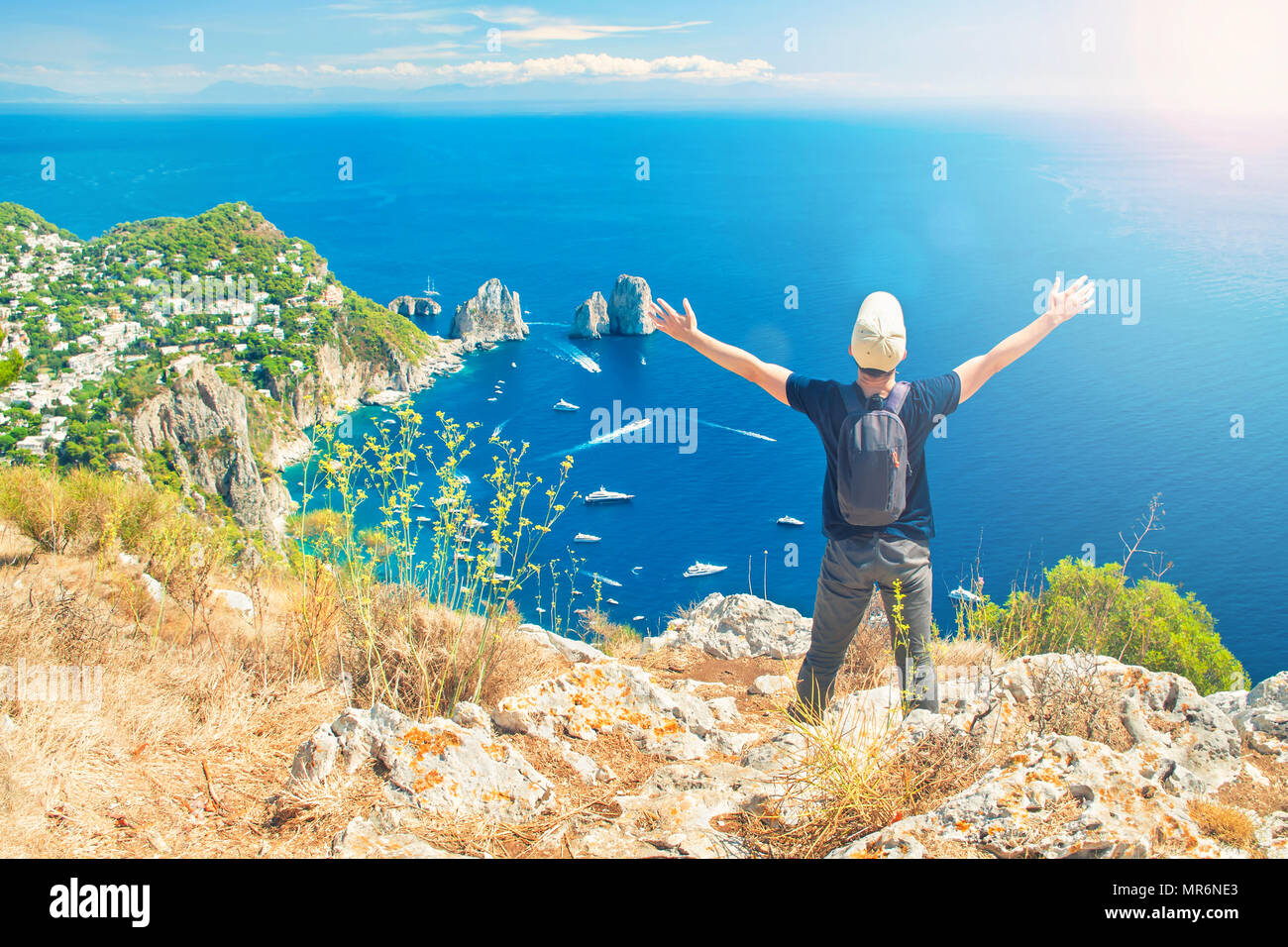 Young caucasian homme debout avec son dos à la caméra et les mains en profitant de beau coucher de soleil sur le sommet de la montagne Solaro sur fameux Faraglioni ro Banque D'Images