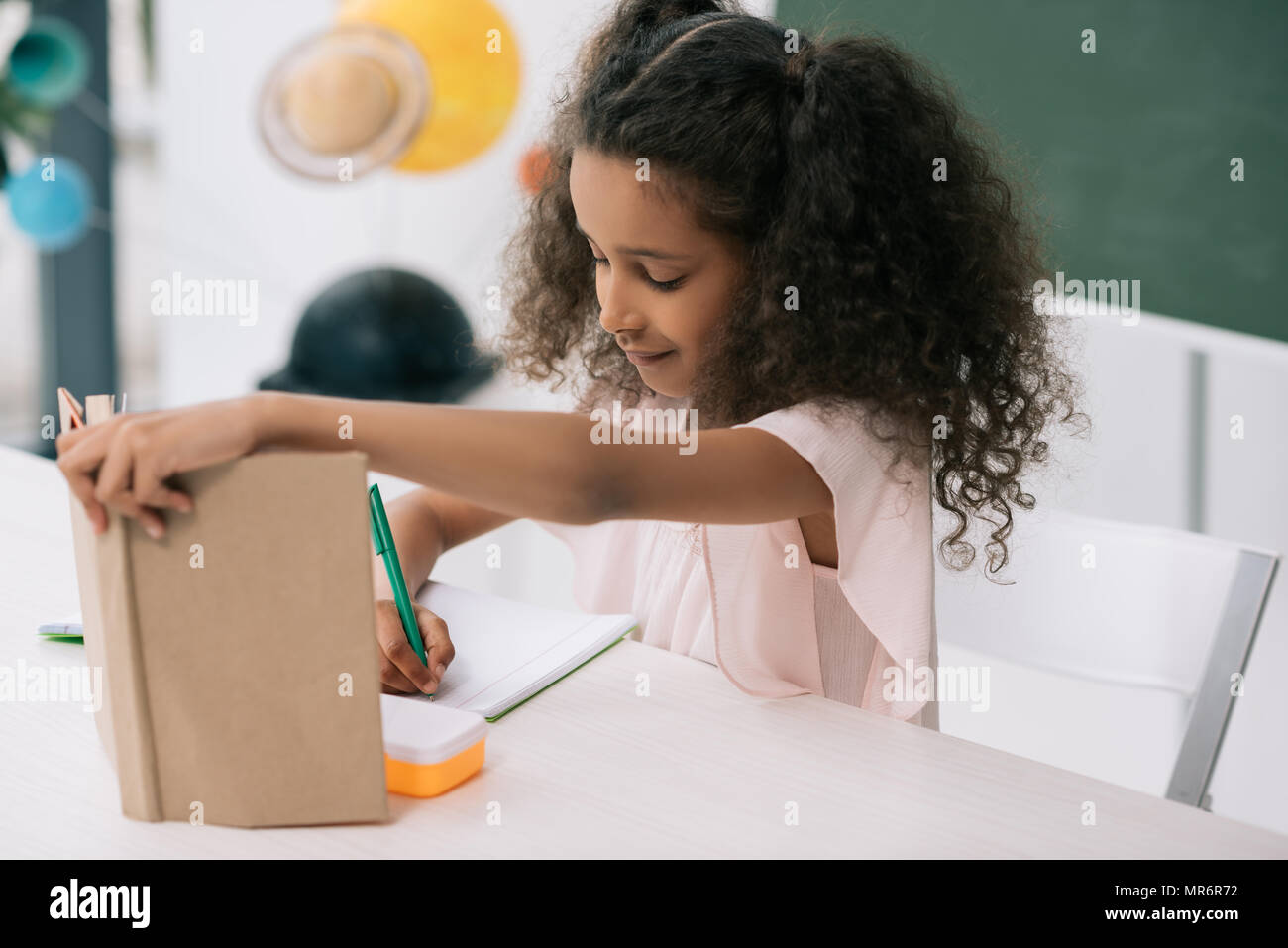 L'accent african american schoolgirl holding manuel et expression écrite exercice at lesson Banque D'Images