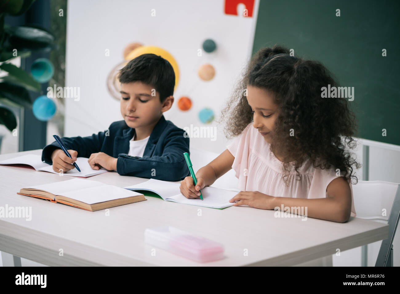 Porté à l'exercice d'écriture élèves multiethnique leçon en classe Banque D'Images