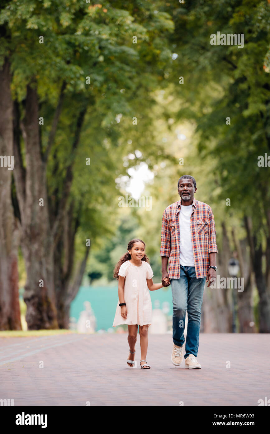 African American girl holding hands avec grand-père et walking in park Banque D'Images
