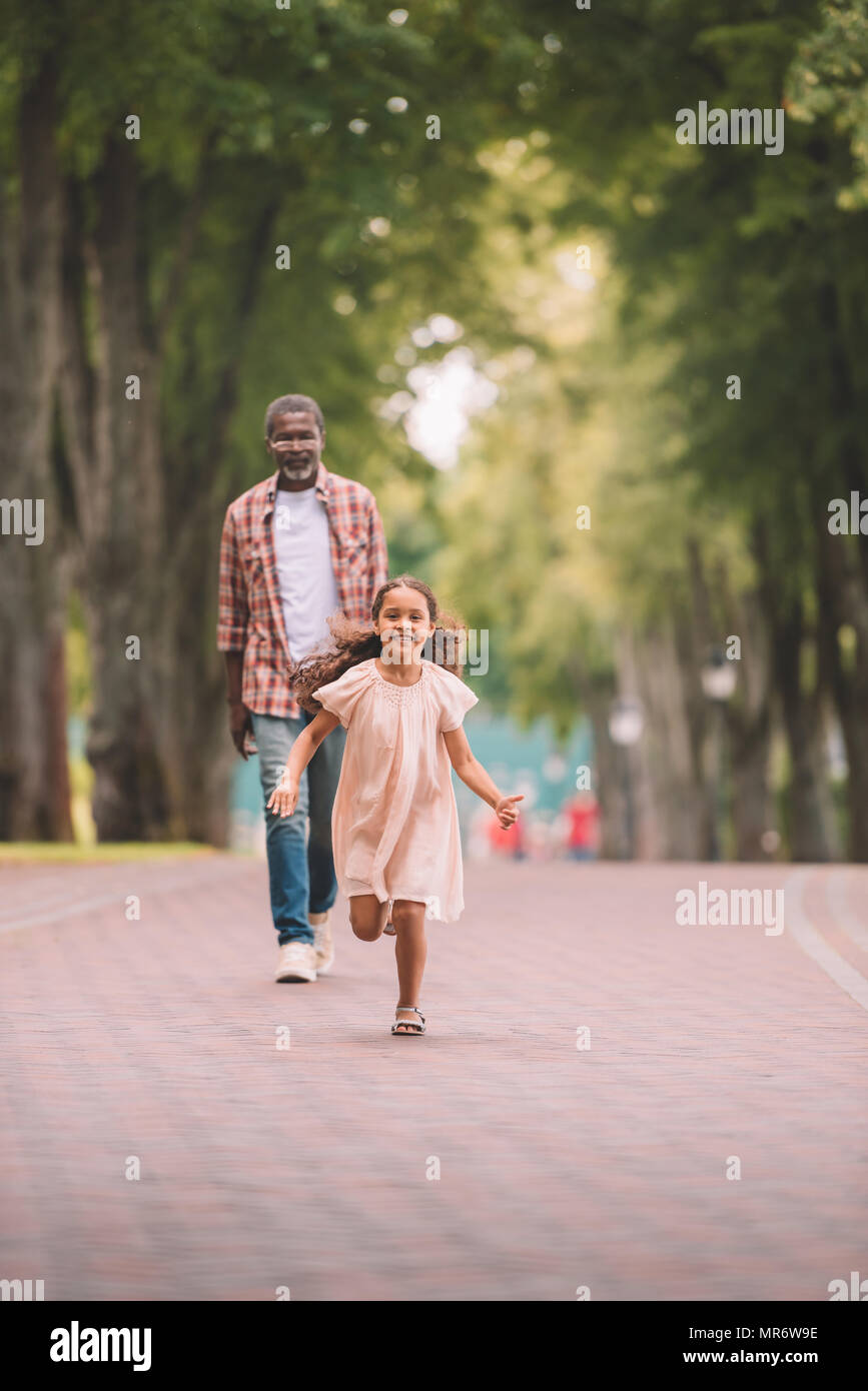 Happy african american petit-enfant en marche et passer du temps avec son grand-père dans la région de park Banque D'Images