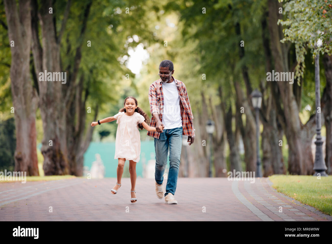 Happy african american petite-fille main dans la main avec son grand-père et walking in park Banque D'Images